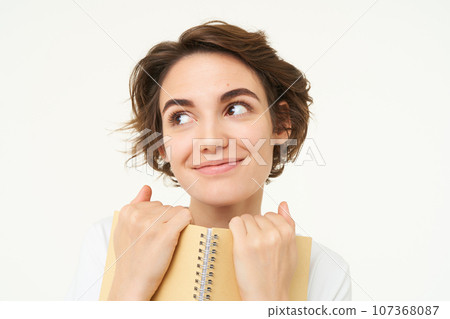 Portrait of happy woman with planner, holding notebook, reading notes and smiling, standing over white background Portrait of happy woman with planner, holding notebook, reading notes and smiling, standing over white background 107368087