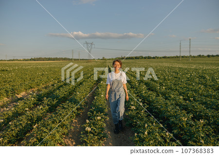 Professional female agronomist in uniform on potato field background. Agriculture concept 107368383
