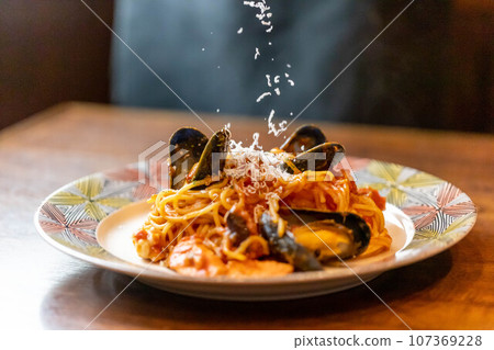 Sprinkle grated cheese on pescatore pasta Sprinkle grated cheese on pescatore pasta 107369228