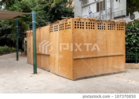 Wooden sukkah in a yard of a residential building in Israeli town during jewish holiday Sukkot Wooden sukkah in a yard of a residential building in Israeli town during jewish holiday Sukkot 107370850