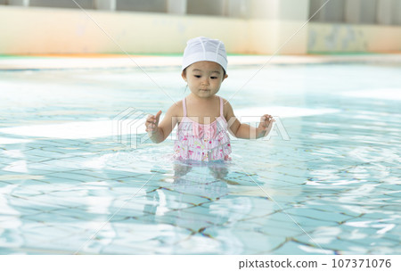 Cute 1 year old girl playing in the pool 107371076