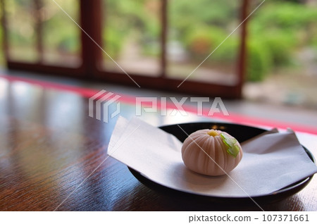 傳統的日本老房子和日本花園,配有日本甜點和冰鎮日本抹茶 傳統的日本老房子和日本花園,配有日本甜點和冰鎮日本抹茶 107371661