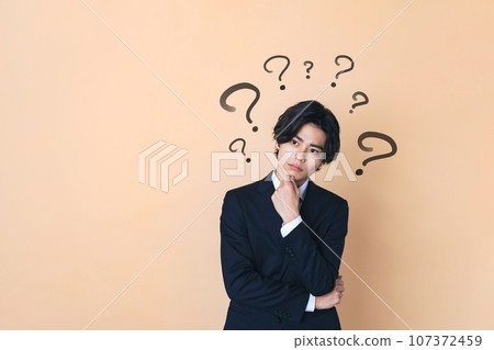 A young businessman wearing a suit who is thinking A young businessman wearing a suit who is thinking 107372459