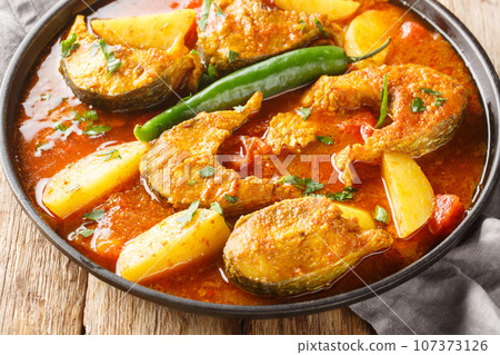 Tasty Asian fish curry seasoned with turmeric, garlic, onions, and grated ginger and Indian spices closeup on the plate. Horizontal Tasty Asian fish curry seasoned with turmeric, garlic, onions, and grated ginger and Indian spices closeup on the plate. Horizontal 107373126