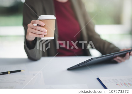 Concept of business office woman working,Businesswoman smile while working about her invesment plan with analyzing document and business investment graph data by using laptop on desk in workstation. 107373272