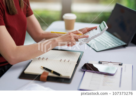 Concept of business office woman working,Businesswoman smile while working about her invesment plan with analyzing document and business investment graph data by using laptop on desk in workstation. 107373276