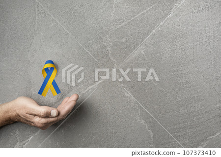 hand with yellow and blue ribbon on marble hand with yellow and blue ribbon on marble 107373410