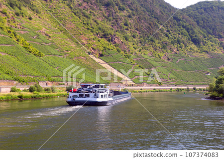 A self-propelled cargo ship goes along the Moselle River on a clear sunny day. A self-propelled cargo ship goes along the Moselle River on a clear sunny day. 107374083