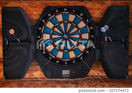 Bright multicolored dartboard hangs on wall. Close-up. Games , entertainment. Excitement, sport. 107374472