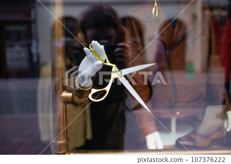 Mannequin hand holding hair scissors from the shopping windows. Minimalism beauty concept 107376222