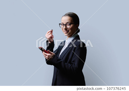 Teenage girl making money gesture, rubbing her fingers, on grey background Teenage girl making money gesture, rubbing her fingers, on grey background 107376245