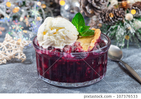 Berry cobbler in glass ramekin with ice cream, Christmas decoration with bokeh, horizontal Berry cobbler in glass ramekin with ice cream, Christmas decoration with bokeh, horizontal 107376533