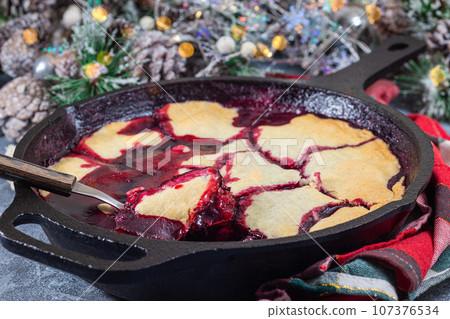 Homemade berry cobbler in cast iron skillet, Christmas decoration with bokeh, horizontal 107376534