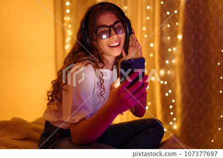 Woman in headphones before bedtime listening online to relaxing music. Remote work, internet concept 107377697