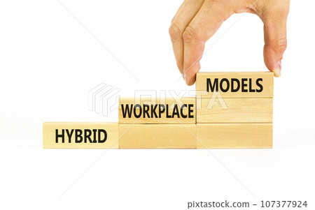 Hybrid workplace models symbol. Concept words Hybrid workplace models on wooden blocks. Businessman hand. Beautiful white background. Business hybrid workplace models quote concept. Copy space 107377924
