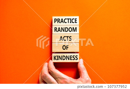 Practice random kind of kindness symbol. Concept words Practice random kind of kindness on wooden block. Beautiful orange background. Businessman hand. Business practice kindness concept. Copy space. 107377952