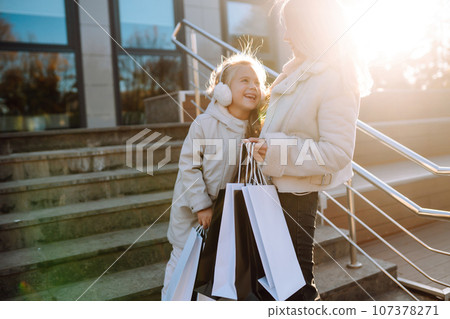 Young mother and little girl with shopping bags after shopping. Spring Style. Consumerism. 107378271