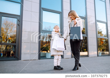 Young mother and little girl with shopping bags after shopping. Spring Style. Consumerism. 107378273