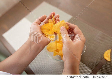 a woman holding a handful of chips while dieting a woman holding a handful of chips while dieting 107378660