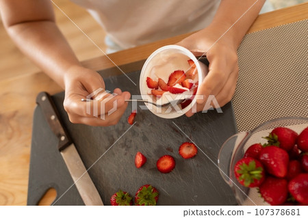women's hands make a breakfast of cream and strawberries 107378681