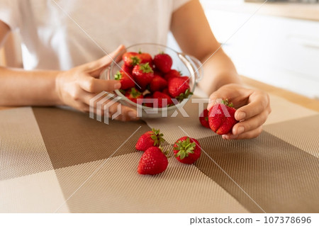 a woman picks strawberries to make breakfast 107378696