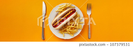 Traditional hot dog with french fries in plate on orange background. Restaurant menu Traditional hot dog with french fries in plate on orange background. Restaurant menu 107379531