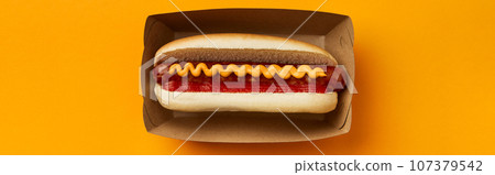 Classic hot dog with wurst, ketchup and mustard on orange background. Restaurant menu delivery tacke away concept 107379542