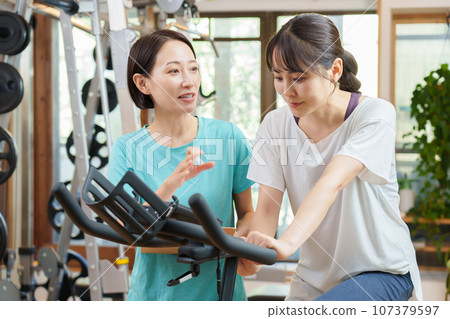 騎健身自行車的女人和教練 107379597