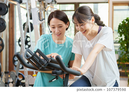 騎健身自行車的女人和教練 107379598