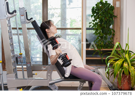 Woman doing muscle training with dumbbells 107379678