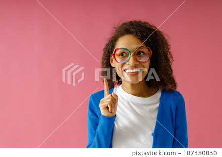 Portrait of excited young woman holding index finger up with great new idea on red studio background 107380030