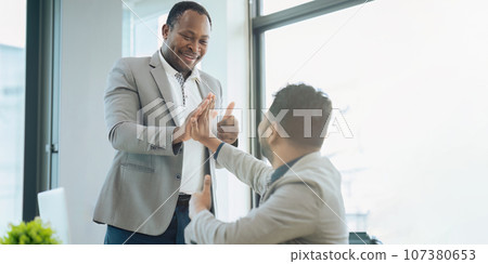 Two diverse businessman professionals celebrating teamwork in an office Two diverse businessman professionals celebrating teamwork in an office 107380653