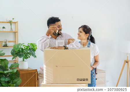 House Ownership. Portrait Of Happy Indian Married Holding Showing Key Standing In New home 107380925