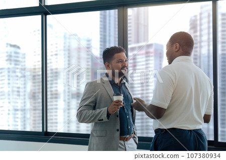 Two happy diverse coworker discussing while coffee breaking about meeting Two happy diverse coworker discussing while coffee breaking about meeting 107380934