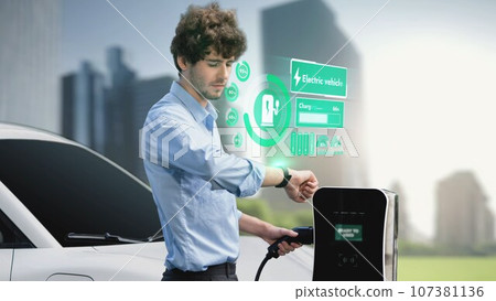 Businessman check EV car battery status on smartwatch hologram. Peruse 107381136