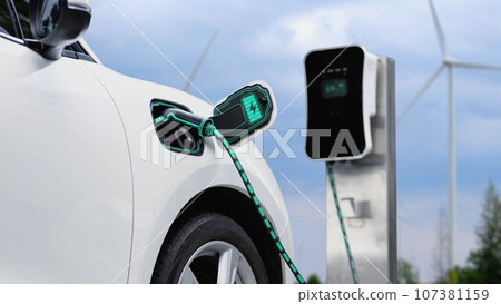 Electric car recharging energy from charging station in wind turbine farm.Peruse Electric car recharging energy from charging station in wind turbine farm.Peruse 107381159
