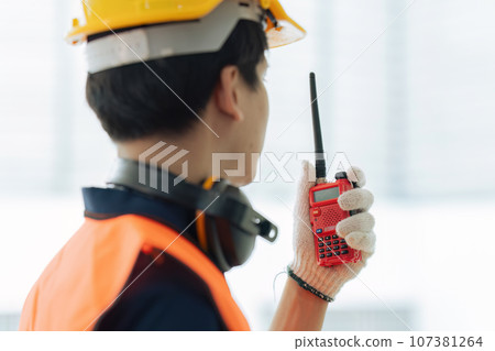 Civil engineer construction leader holding and using walkie-talkie on construction site 107381264