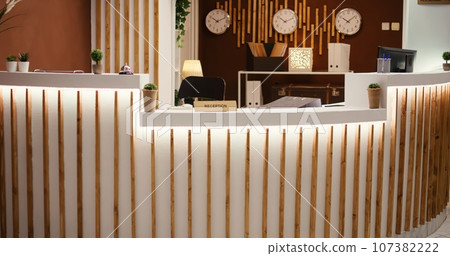 Rack focus shot of stylish travel vacation accommodation lounge interior with posh green furniture ready to welcome guests. Empty luxury hotel foyer with check in reception front desk Rack focus shot of stylish travel vacation accommodation lounge interior with posh green furniture ready to welcome guests. Empty luxury hotel foyer with check in reception front desk 107382222