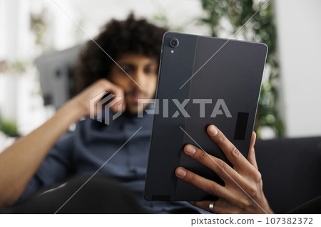 Young arab entrepreneur reading article on digital tablet while working in business office. Start up company executive manager checking project marketing strategy presentation 107382372