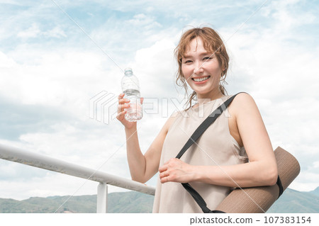 Woman with water and yoga mat, exercise, diet, hydration, hydrogen water, detox Woman with water and yoga mat, exercise, diet, hydration, hydrogen water, detox 107383154