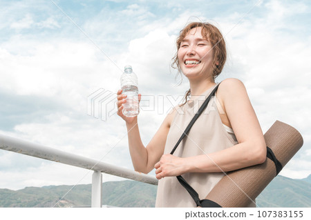 Woman with water and yoga mat, exercise, diet, hydration, hydrogen water, detox Woman with water and yoga mat, exercise, diet, hydration, hydrogen water, detox 107383155