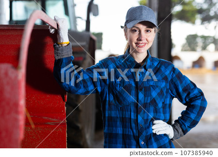 Portrait of woman next to tractor in the backyard of farm Portrait of woman next to tractor in the backyard of farm 107385940