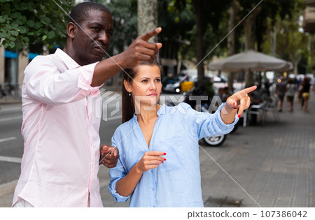 Man helping young woman to find right address Man helping young woman to find right address 107386042