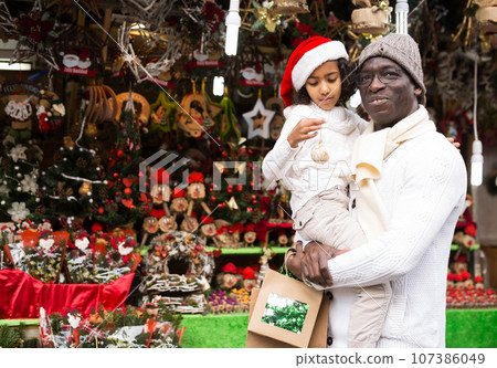 African american man with daughter in buying Christmas decoration African american man with daughter in buying Christmas decoration 107386049