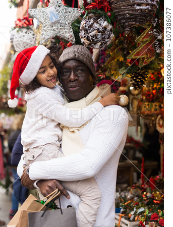 Man holding daughter, looking around at Christmas fair Man holding daughter, looking around at Christmas fair 107386077