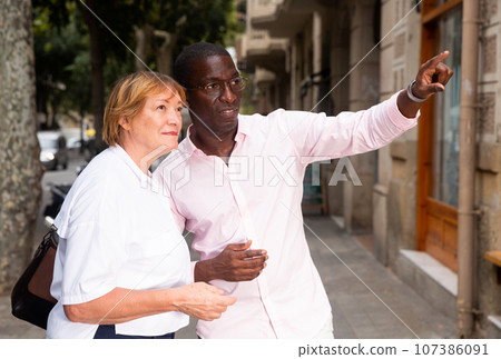 Man helping middle aged woman to find way Man helping middle aged woman to find way 107386091