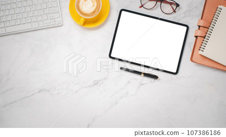 Office desk workplace with blank screen digital tablet, keyboard, eyeglass, pen, noebook and cup of coffee, Top view flat lay with copy space. Office desk workplace with blank screen digital tablet, keyboard, eyeglass, pen, noebook and cup of coffee, Top view flat lay with copy space. 107386186