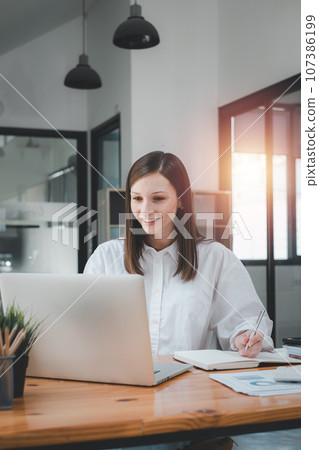 Beautiful woman using laptop while sitting at her working place. Concentrated at work.. 107386199