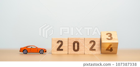 2023 flipping to 2024 year block with car model on table. Automobile Tax, Car Insurance, Financial, vehicle Repair and Maintenance and New Year concept 107387338