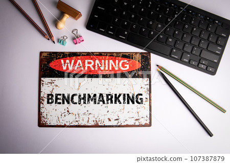 Benchmarking Concept. Warning sign and computer keyboard on a white background Benchmarking Concept. Warning sign and computer keyboard on a white background 107387879